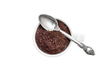 Full cup of ground coffee with spoon on white. Top view.