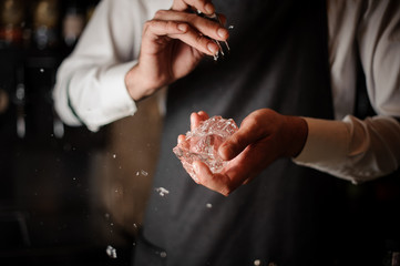 Professional male bartender breaking an ice cube with a special tool