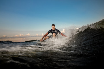 Brunet man riding on the wakeboard on the bending knees