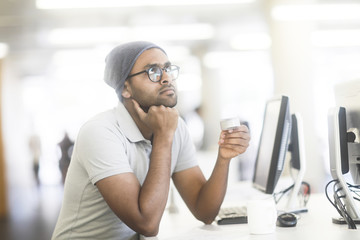 Junger Mann mit Mütze und Rotor sitzend in einem Büro