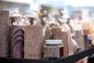 Natural, handmade candles in different shapes standing in shelf sorted by colors. Concept of gifts  

