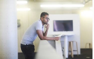Fototapeta premium Junger Mann an einer Brüstung in einem Büro stehend