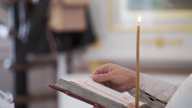 Priest praying with Bible book in church at ceremony