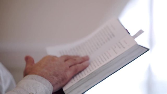Priest praying with Bible book in church at ceremony
