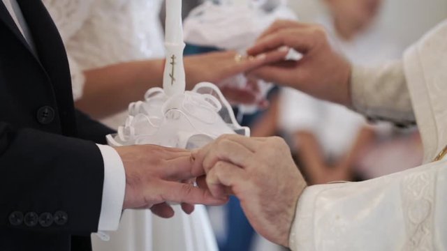 Priest praying in church at wedding ceremony and put on rings for newlyweds bride and groom