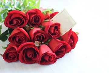 red roses bouquet with black tag on white wood background for valentine mother's day or birthday with copy space