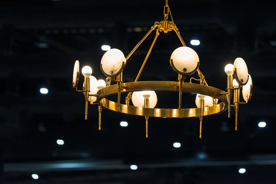 Modern golden chandelier in the light bulbs hanging from the ceiling luxury retro style on dark background