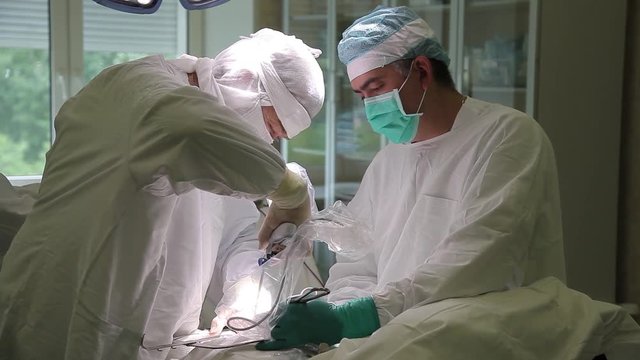 Two Doctors in protective clothing performing surgery use sterilized equipment