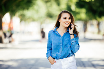 Portrait of woman walking and talking on the mobile phone in a city street