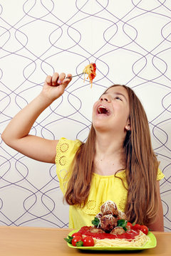 The girl eats spaghetti with meatballs