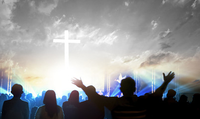 Worship and praise concept: Silhouette many people raised hands over sunset background