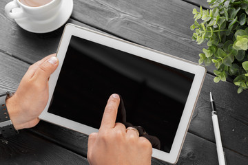 hands of a man holding blank tablet device over a wooden workspace table