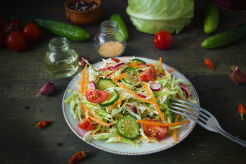 Fresh dietary salad of cucumbers, tomatoes, cabbages, radishes, carrots with sesame seeds, olive oil, garlic and herbs. Healthy meal. Detox and vegetarian concept.