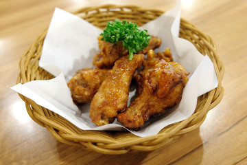 Fried chicken wings in white plate on wooden table..