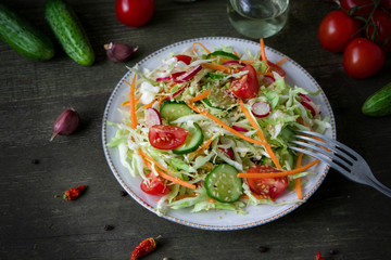 Fresh dietary salad of cucumbers, tomatoes, cabbages, radishes, carrots with sesame seeds, olive oil, garlic and herbs. Healthy meal. Detox and vegetarian concept.
