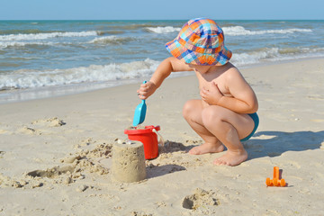 Cute little boy is building sand castle on the seashore