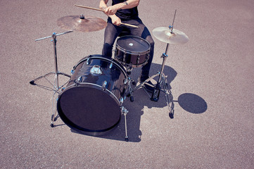 Fototapeta na wymiar cropped shot of tattooed drummer playing drums on street