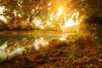 Fototapeta na wymiar Beautiful sunny autumn landscape with reflection in the water and sun shine