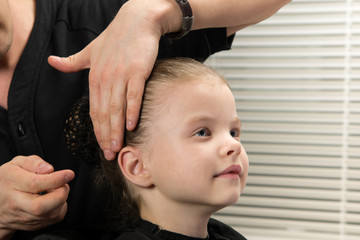 hair stylist makes the girl a hairstyle bun