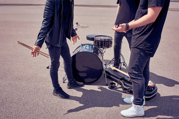 partial view of rock band in black clothing standing near musical instruments on street