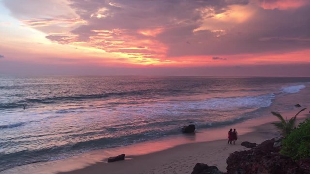 Amazing sunset over tropical beach Varkala, India. Kerala beach and dog, multiple colors colorful sunset sky and motion blurred Laccadive Sea at Papanasam beach India. Summer orange sunset a rocky