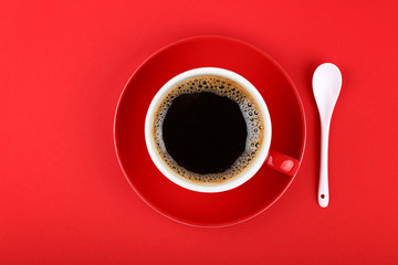 Full cup of black coffee and saucer over red