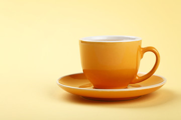 Yellow cup of tea or coffee on saucer