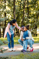 Fototapeta premium african american parents looking at daughter on path in park