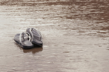 Flip flop sandals on the golden sand at the tropical beach at sunrise. Summer time concept.