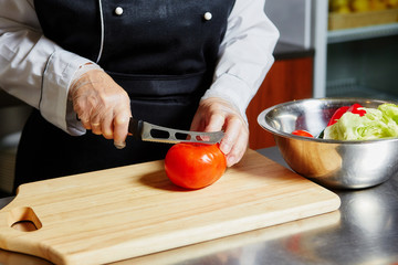 Chef cutting tomato on cutting board