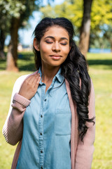 attractive african american woman posing with closed eyes in park