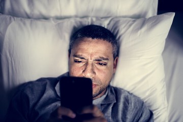 Man using phone on a bed