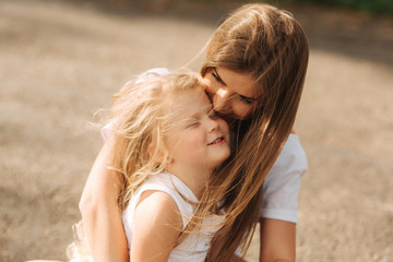 Happy loving family. Mother and her daughter child girl playing and hugging. alley of big trees. close up view