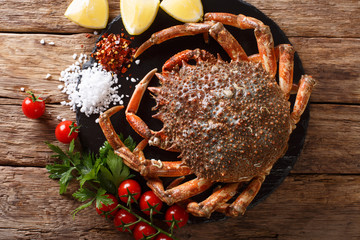 Luxurious Raw spider crab surrounded by fresh tomatoes, lemon, herbs and spices close-up. Horizontal top view