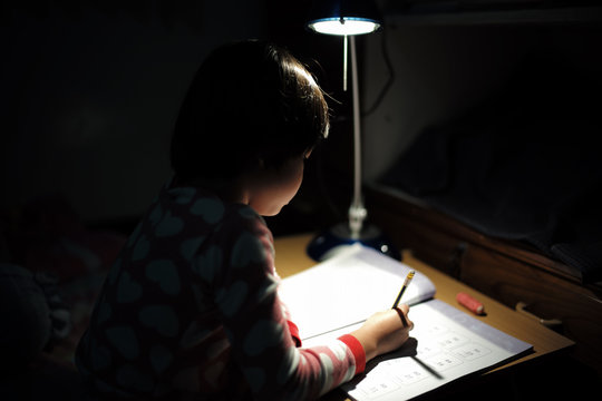 Portrait of little Asian girls doing her homework under the lighting lamp