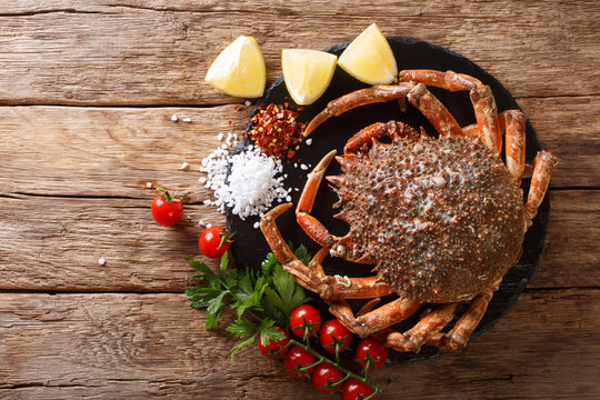 Seafood background: raw edible spider crab with ingredients close-up on a wooden table. Horizontal top view
