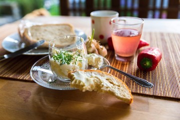 Cottage cheese in glass bowl, fruit juice drink, bread, red pepper. Small healthy breakfast on garden table with nice blurry background.