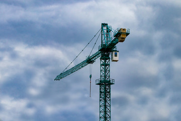 Construction cranes on the construction site against the blue sky and clouds