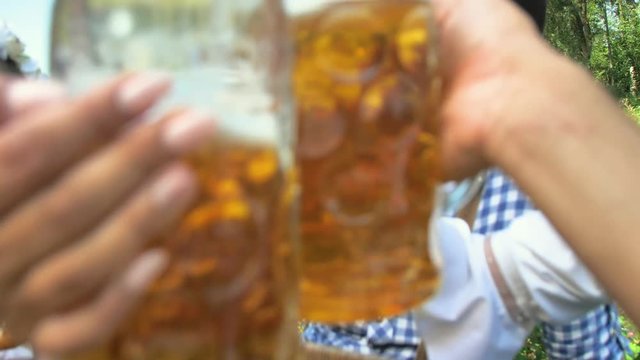 Oktoberfest Freunde in Lederhosen und Dirndl trinken Bier an der Isar