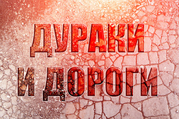 Inscription 'Fools and roads' (in Russian) on concrete cracks abstract texture background. With...