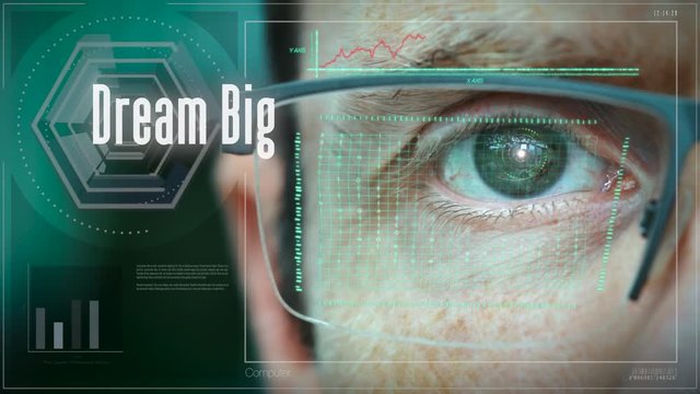 A close up of a businessman eye controlling a futuristic computer system with an Dream Big concept.