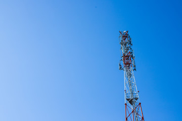 Red and white tower of communications with with a lot of different antennas under clear sky. Telecom Signal Tower.Telecommunications tower cells for mobile communications.Copy space