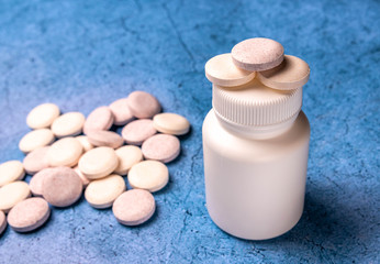 set of round vitamin next to a white bottle on a blue background