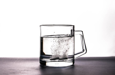 effervescent tablets soluble in water in a transparent cup on a white background.