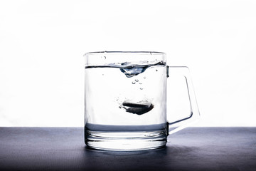 effervescent tablets soluble in water in a transparent cup on a white background.