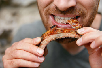 People Eat Food. Man Eating Barbecue Ribs In Grill Bar Closeup