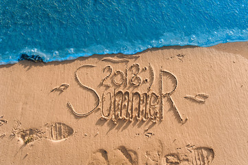 Summer passed the concept. The wave washes away the inscription summer 2018 written on the sand. End of vacation and season.