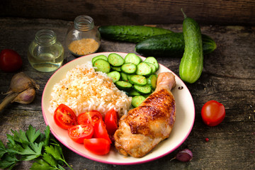 Grilled chicken leg, white rice, slised cucumber with sesame seeds, tomtoes and herbs.