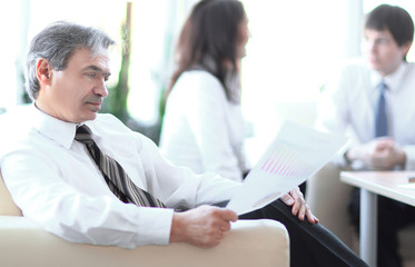 businessman pondering a document sitting in a modern office