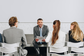 smiling coach looking at business people during training in hub